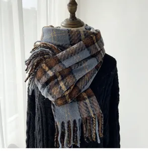 Detailed close-up of the blue and brown plaid autumn winter warm fringed cashmere-like scarf.