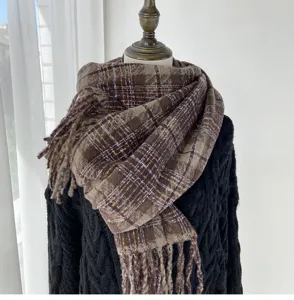Detailed shot of a women's thickened brown plaid scarf with fringe, soft imitation cashmere.