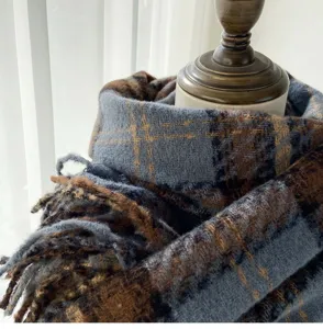 Close-up detail of soft cozy blue and brown plaid winter scarf with fringed edges.