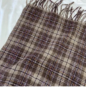Close-up detail of soft brown plaid winter scarf with fringe, stylish cold weather accessory.