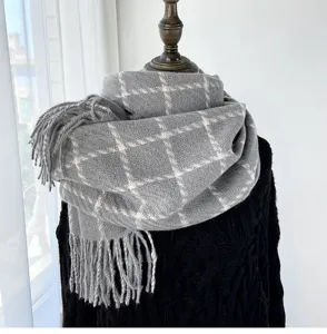 Detailed view of grey plaid winter scarf, soft cashmere feel fabric with cozy fringe trim.