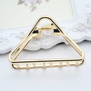 Close-up detail of minimal gold triangle metal hair claw clip for women styling accessory.