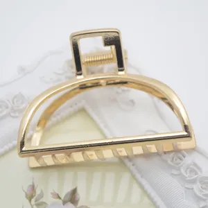 Detail view of a minimalist zinc alloy hair claw clip, large gold geometric hair accessory.