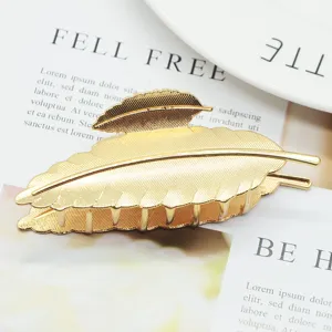 Minimalist gold leaf hair claw clip for women, large metallic hair accessory for styling.