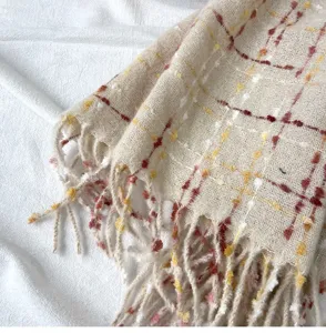 Close-up detail of soft winter plaid scarf with fringe, textured cozy fabric for women.