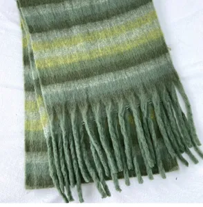 Détail de l'écharpe d'hiver en mohair doux, design rayé vert avec franges élégantes.