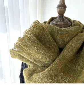 Close-up detail of soft olive green plaid fringed scarf texture for warm winter wear.