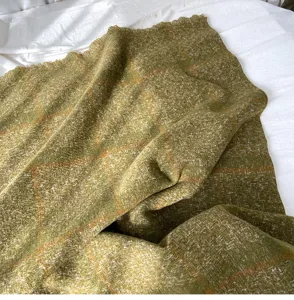 Close-up detail of green plaid cashmere-feel scarf, soft texture and delicate tassel edge.