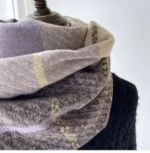 Close-up detail of a thick winter plaid scarf in purple and brown, soft cozy texture.