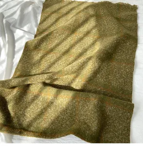 Close-up detail of cozy retro green plaid winter scarf with soft fringe and warm texture.