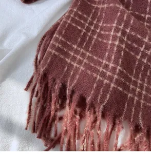 Gros plan détail d'écharpe d'hiver à carreaux avec texture frangée confortable et douce.