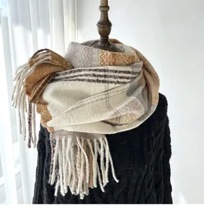 Detailed view of a cozy plaid tassel winter scarf in neutral tones, soft and warm draped style.
