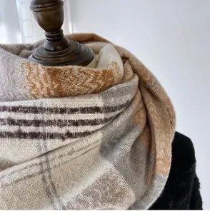 Detailed close-up view of a cozy autumn winter plaid cashmere feel scarf in neutral beige.