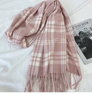 Vue détaillée d'une écharpe à carreaux rose et blanc en imitation cachemire avec franges.