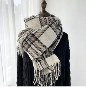 Close-up detail of a classic plaid cashmere-feel winter scarf featuring stylish fringe.