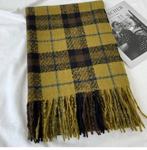 Detail shot of a women's yellow and brown plaid scarf featuring soft fringe and warm knit texture.