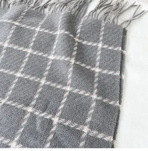 Detail shot of a grey plaid imitation cashmere scarf with fringe, showing soft texture.