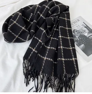 Detailed view of a black plaid fringed scarf, soft and warm winter fashion accessory.