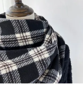 Close-up detail of a classic black and white plaid scarf, soft texture and warm fabric.