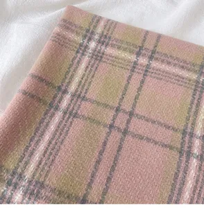 Close-up detail of a soft pink and khaki plaid winter scarf, cozy cashmere-feel fabric.