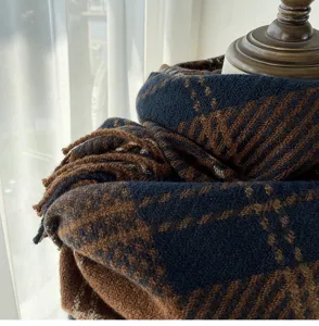 Gros-plan détaillé d'une écharpe en tricot à carreaux bleu marine et marron drapée.