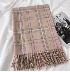 Pink plaid scarf detail showing soft cashmere-like texture and fringed hem in a cozy setup.