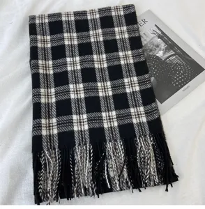 Detailed view of black and white plaid scarf with cozy tassels, classic winter accessory.