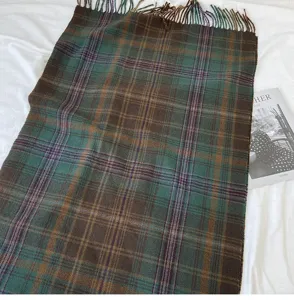 Close-up detail of retro plaid scarf with cozy green and brown pattern and fringe edges.