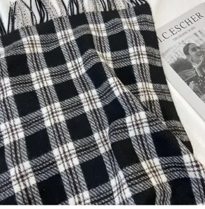 Black and white plaid scarf detail shot, cozy cashmere-feel fabric with elegant fringe edges.