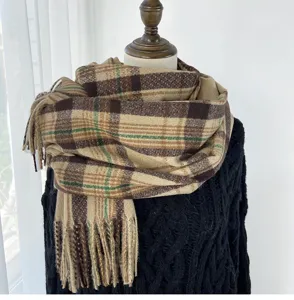 Detail view of the cozy winter plaid scarf featuring brown, beige, and green tones with fringe.
