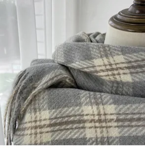Close-up detail of grey plaid imitation cashmere scarf with soft tassel texture and warm winter wear.