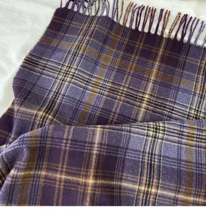 Detailed close-up shot of a cozy retro purple plaid winter scarf with elegant fringe.