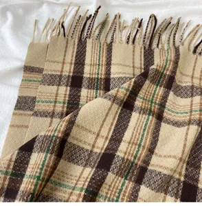 Close-up detail of cozy winter plaid scarf with fringe tassels, soft cashmere feel texture.