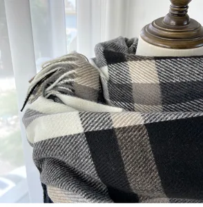 Cozy black white grey plaid scarf close-up, soft imitation cashmere fringe neckerchief.