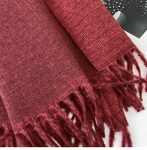 Close-up detail view of soft red winter tassel scarf, showing warm knitted texture clearly.