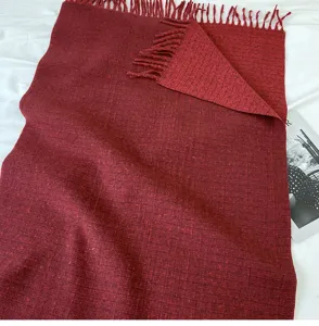Red cashmere-feel winter scarf detail showing soft fabric texture, cozy fringed edge and warm fold.