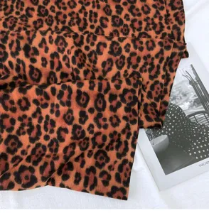 Close-up detail of classic leopard print faux cashmere scarf, soft texture and warm tone.