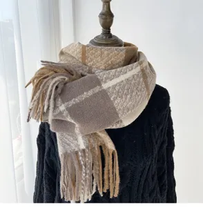 Close-up of winter plaid scarf with fringe, soft cozy fabric texture detail in neutral tones.
