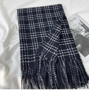 Vue détaillée d'une écharpe d'hiver classique à carreaux noirs et blancs avec franges.