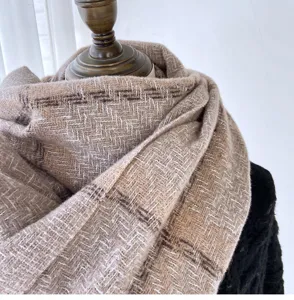 Close-up view of a cozy brown herringbone winter scarf, soft cashmere feel texture detail.