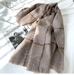 Close-up detail of a soft brown herringbone patterned scarf with elegant fringe trim.