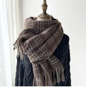 Détail écharpe hiver à carreaux marron, texture tricot douce avec franges élégantes.
