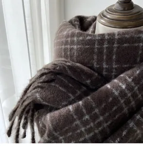 Vue détaillée d'une écharpe à carreaux d'hiver marron confortable avec franges classiques.