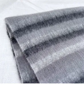 Gros plan détaillé d'une écharpe en mohair à carreaux gris, texture duveteuse et chaude.