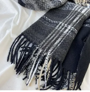 Close-up detail of black grey plaid winter scarf with tassel fringe soft texture warm wrap