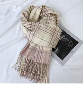 Vista dettagliata di una sciarpa invernale a quadri beige e rosa con frange, stile accogliente.
