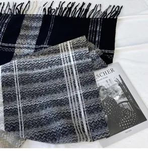 Detailed close-up of a classic black, white and grey plaid fringe scarf, soft texture.