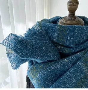 Detailed close-up view of a cozy blue plaid winter scarf featuring elegant fringe ends.