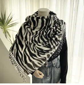 Detailed close-up view of the black and white zebra pattern cashmere-feel scarf with fringe.
