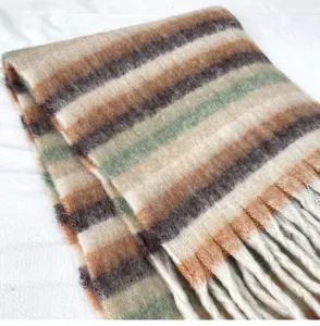 Gros-plan détaillé de l'écharpe douce et duveteuse en mohair à rayures avec des franges élégantes.